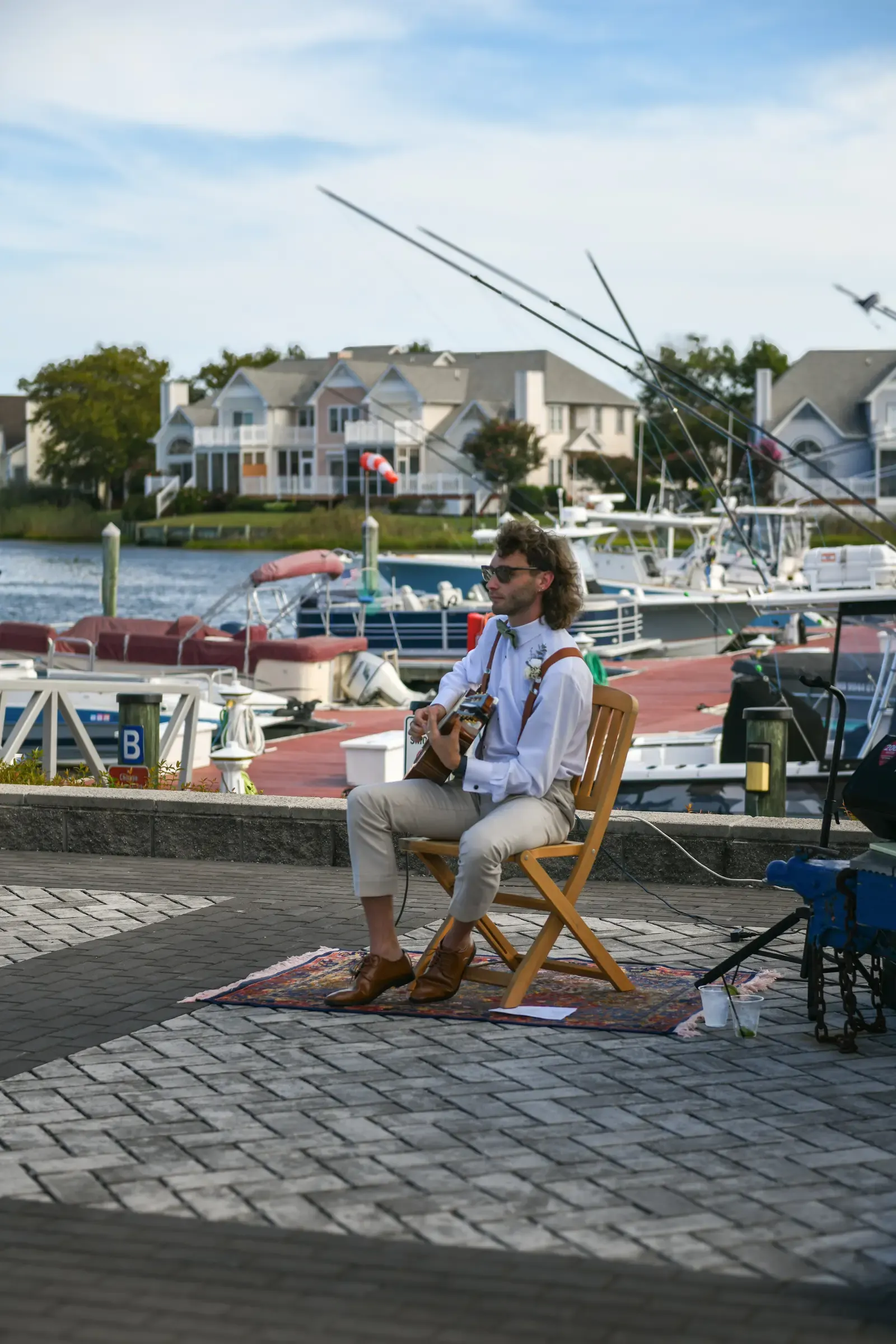 Mathew seated with his guitar and music equipment beside the waterfront.